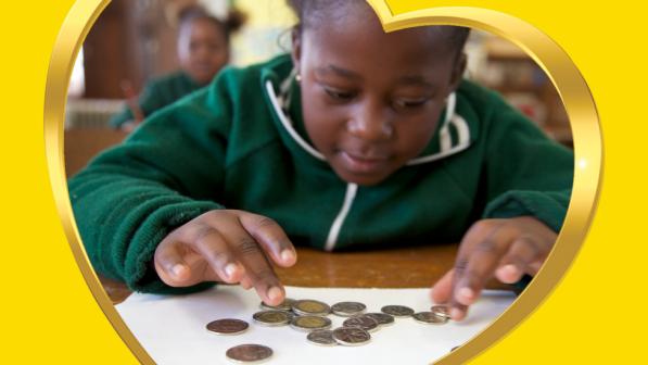 A boy doing maths with coins on his desk