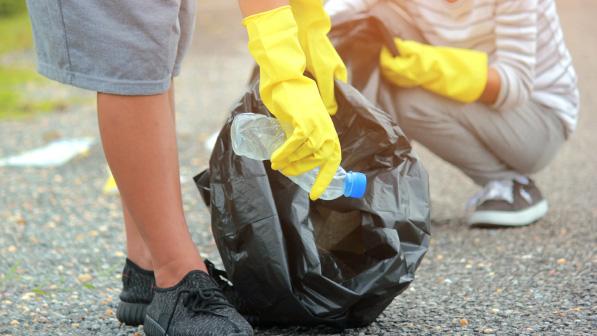 2 teenagers picking up plastics on a road